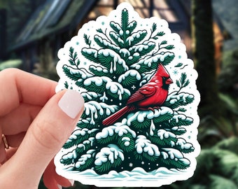 Escena de invierno detallada con cardenal rojo vibrante en pino nevado - pegatina de vinilo impermeable de 2 pulgadas