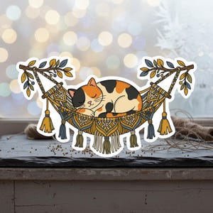 May include: A sticker featuring a calico cat sleeping peacefully in a macrame hammock. The hammock is decorated with tassels and intricate patterns in shades of gold, blue, and cream. The cat has orange, black, and white fur.