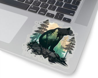 May include: A sticker featuring a black bear with a forest design inside its silhouette. The bear is standing on a rock with trees and foliage in the background. The sticker is on a laptop.