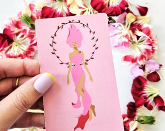 Pode incluir: Uma carta de tarô rosa com as palavras "XXI • THE WORLD" na parte inferior. A carta apresenta uma ilustração de uma mulher com cabelo rosa e um vestido rosa, rodeada por uma coroa. A carta é rodeada por pétalas de flores vermelhas e brancas.