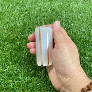 May include: White selenite crystal wand with copper wire wrapped around it. The wand is about 5 inches long and has a smooth, polished surface.