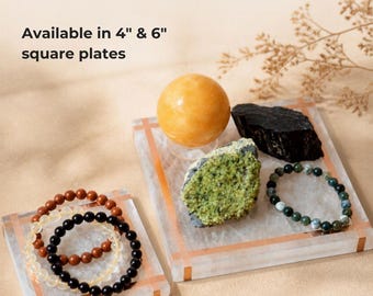 May include: Two square plates with copper-colored grid lines, available in 4" & 6" sizes. The larger plate holds a yellow sphere, a black raw stone, a green textured mineral, and a green beaded bracelet. The smaller plate holds three beaded bracelets.