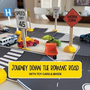 May include: A black and white road with toy cars and trucks, including a yellow dumper truck, a red truck, a green construction vehicle, and a white van. There are also yellow and red traffic signs with the text "SPEED LIMIT 45", "WORK ZONE", and "SPEED LIMIT 15". The text "JOURNEY DOWN THE ROMANS ROAD WITH TOY CARS & BIKES!" is on a yellow banner.