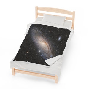 Pu&ograve; includere: Un letto singolo bianco con una struttura in legno e un piumino bianco. Il piumino ha una stampa in bianco e nero di una galassia con una nebulosa a spirale.