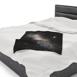 Pu&ograve; includere: Un letto bianco con una testiera nera e una coperta bianca con una stampa di galassia. La stampa di galassia presenta una nebulosa vorticosa con stelle e uno sfondo scuro.