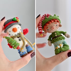 Pode incluir: Figuras de boneco de neve e elfo de crochê. O boneco de neve tem um chapéu cinza, nariz laranja e segura uma árvore de Natal verde. O elfo usa uma roupa verde e um chapéu vermelho e verde. Ambos têm pequenos sinos dourados.