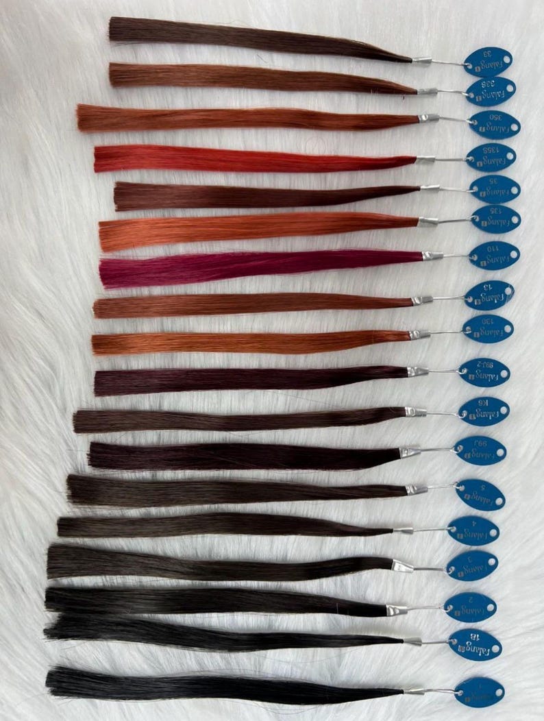 May include: A collection of hair color swatches, each with a different shade of brown, red, and black. Each swatch is attached to a blue tag with a silver wire. The tags have the word "Falang" printed on them.