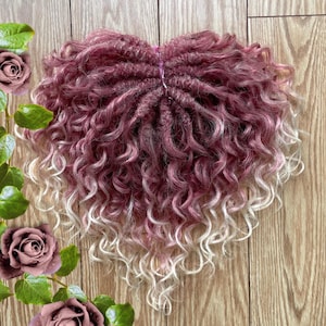 May include: A set of pink and blonde ombre curly hair extensions. The hair is in a loose, wavy style and is perfect for adding volume and length to your hair.