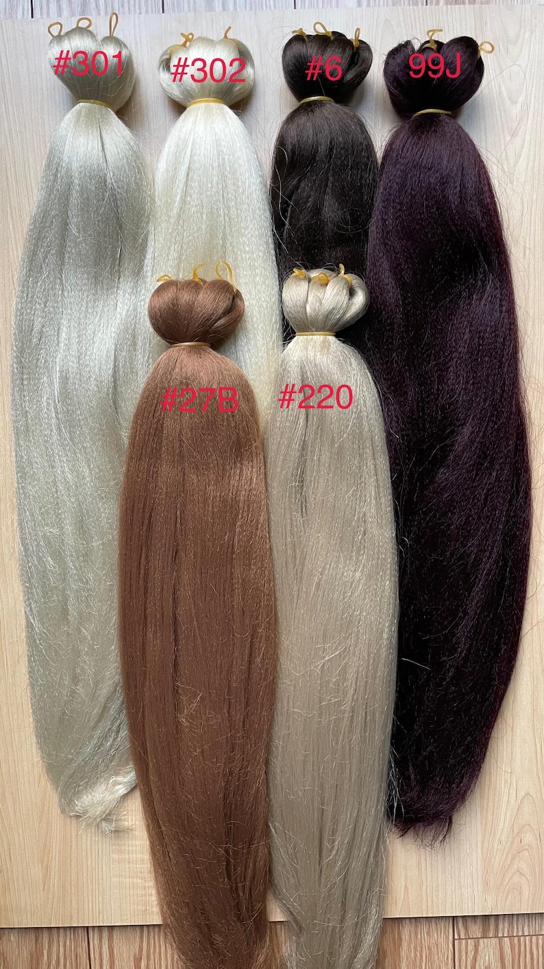 May include: An assortment of synthetic braiding hair extensions in various colors. The colors include silver, white, black, brown, and deep purple. Each bundle is labeled with a number. The hair is bundled at the top with a rubber band.