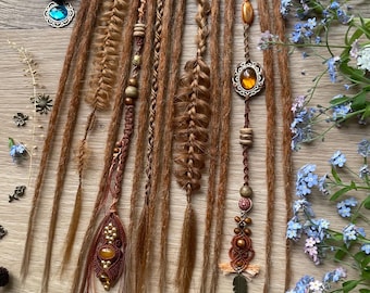 May include: A set of light brown synthetic dreadlocks attached to a white lace band. The dreadlocks feature various textures including braids, twists, and decorative accents such as amber-colored beads, metal charms, and intricate macrame detailing.