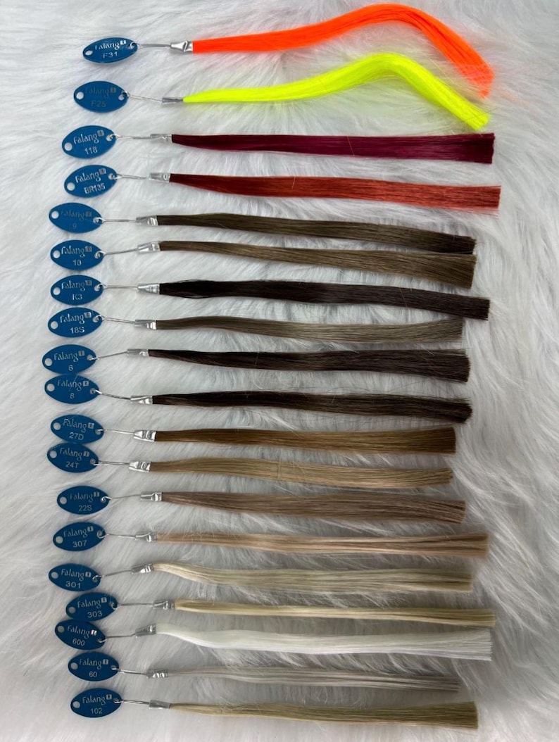 May include: A collection of hair extensions in various colors, including bright orange, yellow, burgundy, and shades of brown and blonde. Each extension is attached to a small, blue tag with a silver wire.