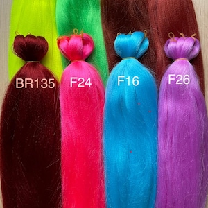 May include: A collection of colorful synthetic braiding hair bundles in various shades, including bright green, pink, blue, and purple. Each bundle is labeled with a code, such as F25, F12, and F24. The hair is arranged vertically, showcasing the vibrant colors.