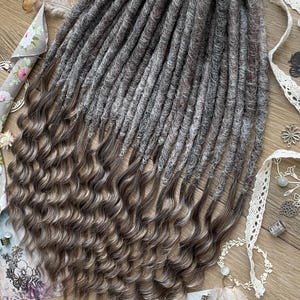 May include: A set of long, gray and brown synthetic dreadlocks with a wavy texture. The dreadlocks are arranged in a bundle and are ready to be installed.