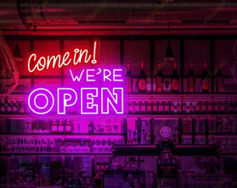 May include: Pink neon sign with the text "Come in! We're Open" hanging above a bar counter with bottles of liquor on shelves behind it.