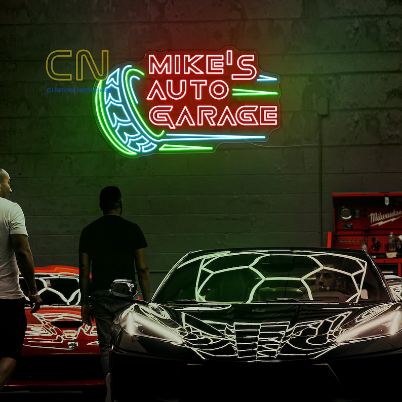 May include: A neon sign with the text "MIKE'S AUTO GARAGE" in red and green letters. The sign is shaped like a tire with a green and blue outline. The sign is mounted on a gray brick wall. Two people are standing in front of the sign, looking at it.