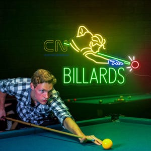 May include: A neon sign with the word "BILLARDS" in green, and a neon figure of a person playing pool. A person in a plaid shirt is aiming a pool cue at a yellow ball on a green pool table.