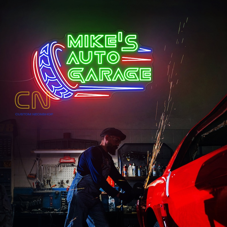 May include: A neon sign with the text "Mike's Auto Garage" in green and blue lettering. The sign is mounted on a wall in a garage setting. A person is working on a red car in the foreground.