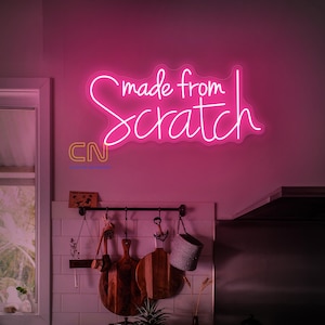 May include: Pink neon sign with the text "made from scratch" on a white wall in a kitchen setting.