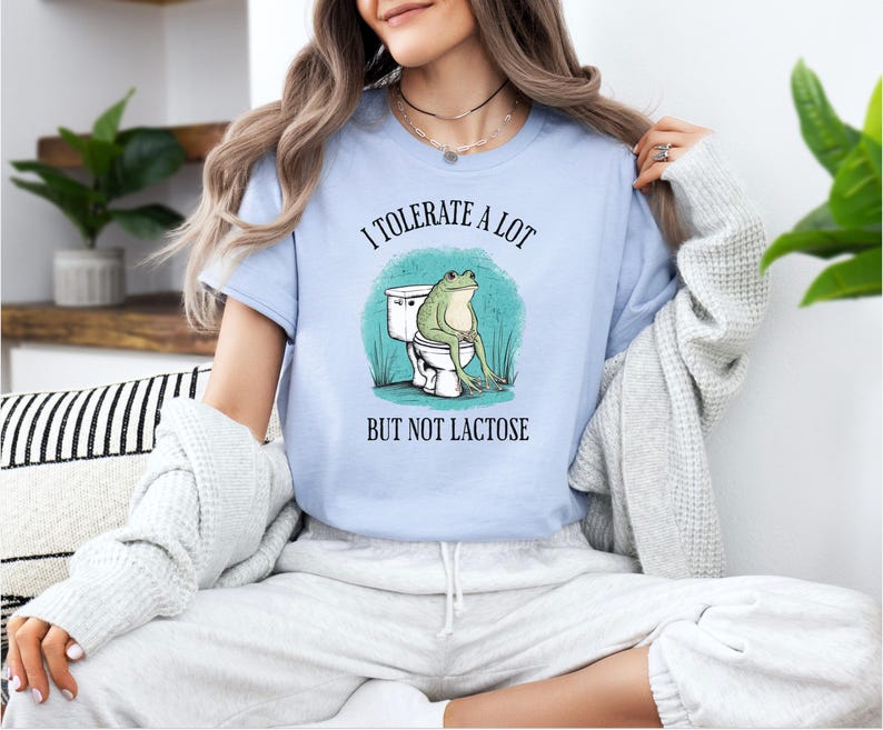 May include: A light blue t-shirt with a frog sitting on a toilet and the text "I tolerate a lot but not lactose".