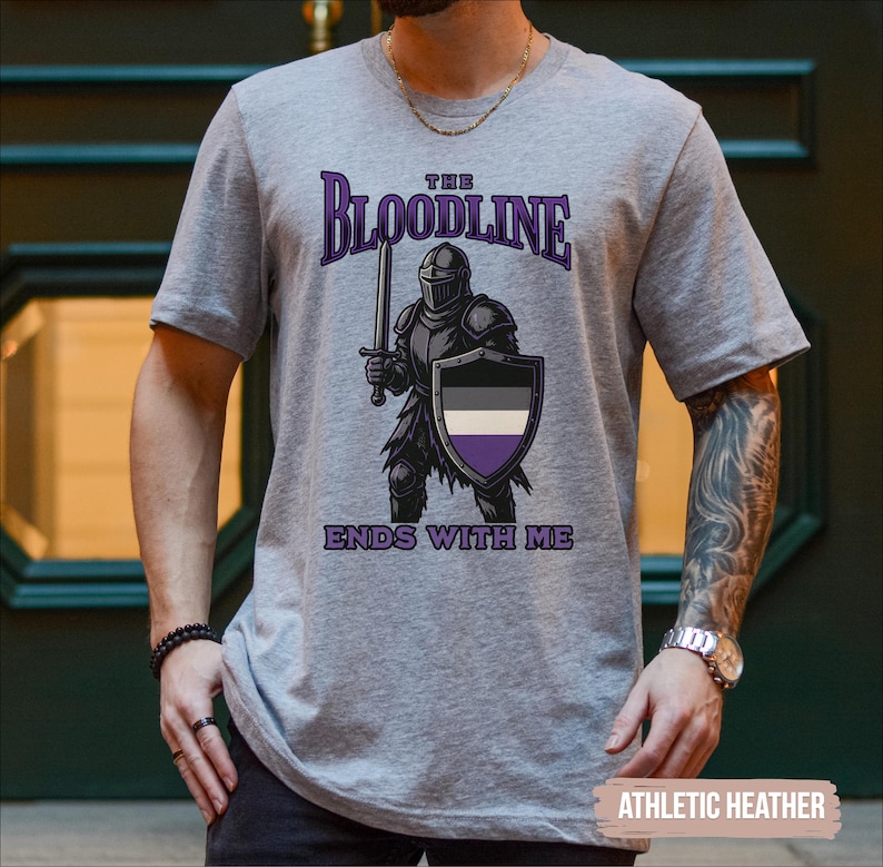 Puede incluir: Una camiseta gris con el texto "The Bloodline Ends With Me" impreso en ella. El dise&ntilde;o presenta un caballero con armadura sosteniendo una espada y un escudo. El escudo tiene los colores de la bandera del orgullo asexual.