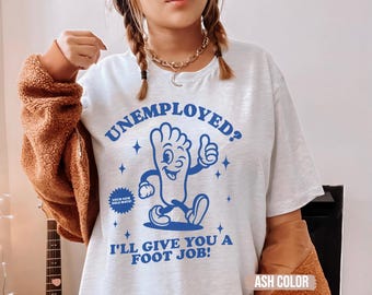 Könnte beinhalten: Aschfarbenes T-Shirt mit dem blauen Text "UNEMPLOYED? I'LL GIVE YOU A FOOT JOB!". Die Grafik zeigt einen Zeichentrickfuß, der einen Daumen hoch gibt. Das Shirt hat auch den Text "YOUR NEW SOLE MATE!"