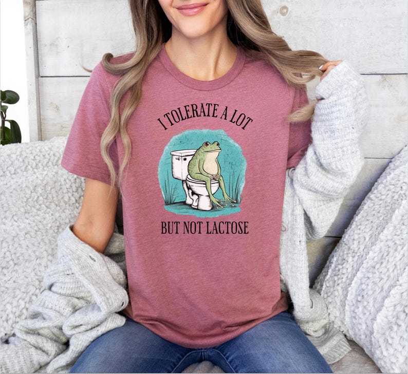May include: A pink t-shirt with the text "I tolerate a lot but not lactose" and a cartoon frog sitting on a toilet.