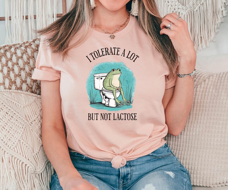 May include: A pink t-shirt with the text "I tolerate a lot but not lactose" and a cartoon frog sitting on a toilet.