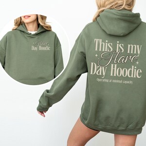 May include: Military green hoodie with the text "This is my Flare Day Hoodie" on the back and "Flare Day Hoodie" on the front. The hoodie has a drawstring hood and a front pocket.
