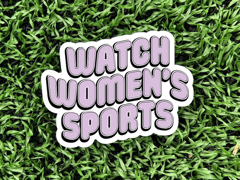 a 3 inch wide vinyl sticker with a purple and black design that reads watch womens sports is displayed on a turf background
