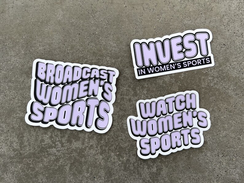May include: Three stickers with a white background and black outlines. The stickers have purple text that reads "Broadcast Women's Sports", "Invest in Women's Sports", and "Watch Women's Sports".