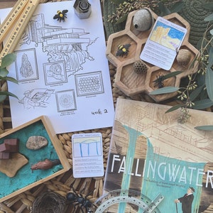 May include: A set of educational materials for a children's learning activity about the Fallingwater house designed by Frank Lloyd Wright. The set includes a coloring page, a book, a protractor, a wooden honeycomb tray with bee-themed elements, and a card with information about the house's design.