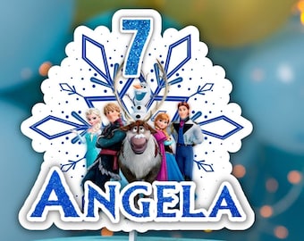 May include: A blue and white frosted cake with a Frozen themed cake topper. The topper features the characters Elsa, Anna, Kristoff, Olaf, and Sven. The topper also includes the number 7 and the name Angela.