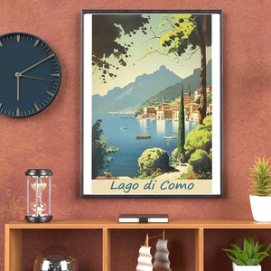 May include: A framed art print of Lago di Como, Italy, with a vintage travel poster style. The artwork depicts a serene lake scene with mountains, buildings, and boats. A dark blue clock, a decorative hourglass, and a small sailboat model are on a wooden shelf.