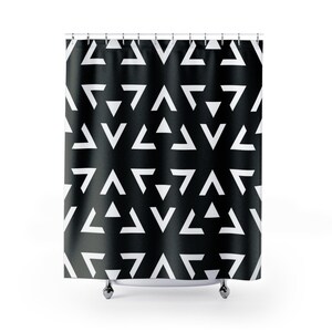May include: Black and white geometric shower curtain. The curtain features a repeating pattern of white triangles against a black background. The curtain is hanging from a metal rod with silver hooks.