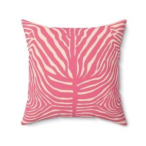 May include: Square cushion with a pink and cream zebra stripe pattern. The cushion features a symmetrical design with curved lines, creating a bold and modern aesthetic. The cushion is a decorative item for a living room or bedroom.