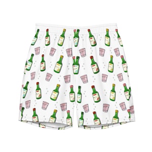 May include: White athletic shorts with a repeating pattern of green bottles and pink glasses. The bottles and glasses have cartoon faces.
