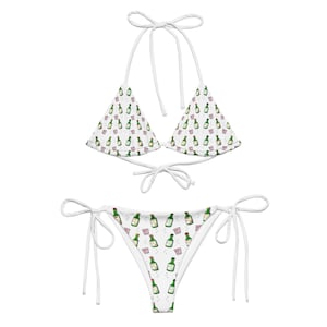May include: White bikini with a green bottle and pink shot glass pattern. The bikini top is a triangle style with adjustable straps. The bikini bottom is a cheeky style with adjustable ties on the sides.