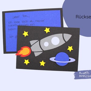 May include: A black card with a rocket, stars, and a planet on a dark blue background. The text "R&uuml;ckseite" is on the top right corner of the card. The text "ALWAYS AMAZING" is on the bottom right corner of the card.