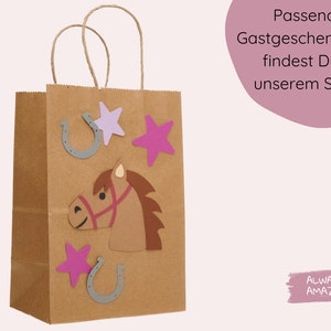 May include: A brown paper gift bag decorated with a horse head, stars, and horseshoes. The bag has a white background with the text "Always Amazing" in pink.