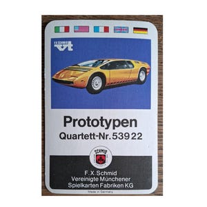 Könnte beinhalten: Eine Vintage-Karte mit einer gelben Sportwagen-Illustration auf blauem Hintergrund. Die Karte trägt die Aufschrift "Prototypen Quartett-Nr.539 22" und das F.X. Schmid-Logo. Oben sind Flaggen verschiedener Länder abgebildet.