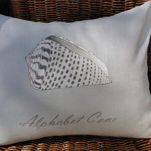 Fodera cuscino in lino azzurro con conchiglia Alphabet Cone dipinta a mano, stile marino per casa al mare o arredi estivi raffinati.