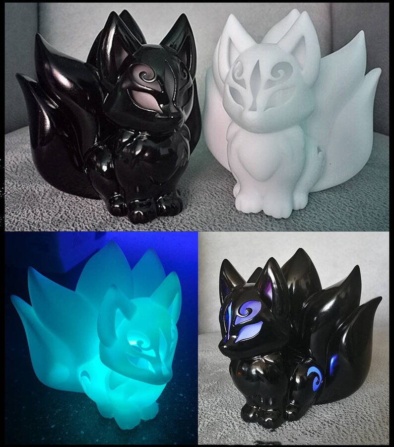 Puede incluir: Una colecci&oacute;n de figuras de zorro en varios colores y estilos. Una es negra con acabado brillante, otra blanca y una tercera brilla con luz azul. Las figuras tienen m&uacute;ltiples colas y detalles faciales intrincados.