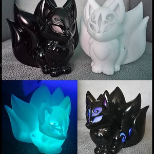 Puede incluir: Colecci&oacute;n de figuras de zorro en varios colores y estilos. Una es negra con acabado brillante, otra blanca y una tercera brilla en azul. Los zorros tienen m&uacute;ltiples colas y detalles faciales intrincados.