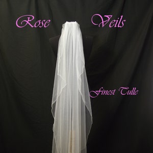 May include: A white bridal veil made of fine tulle, with a single layer and a scalloped edge. The veil is 60 inches long.