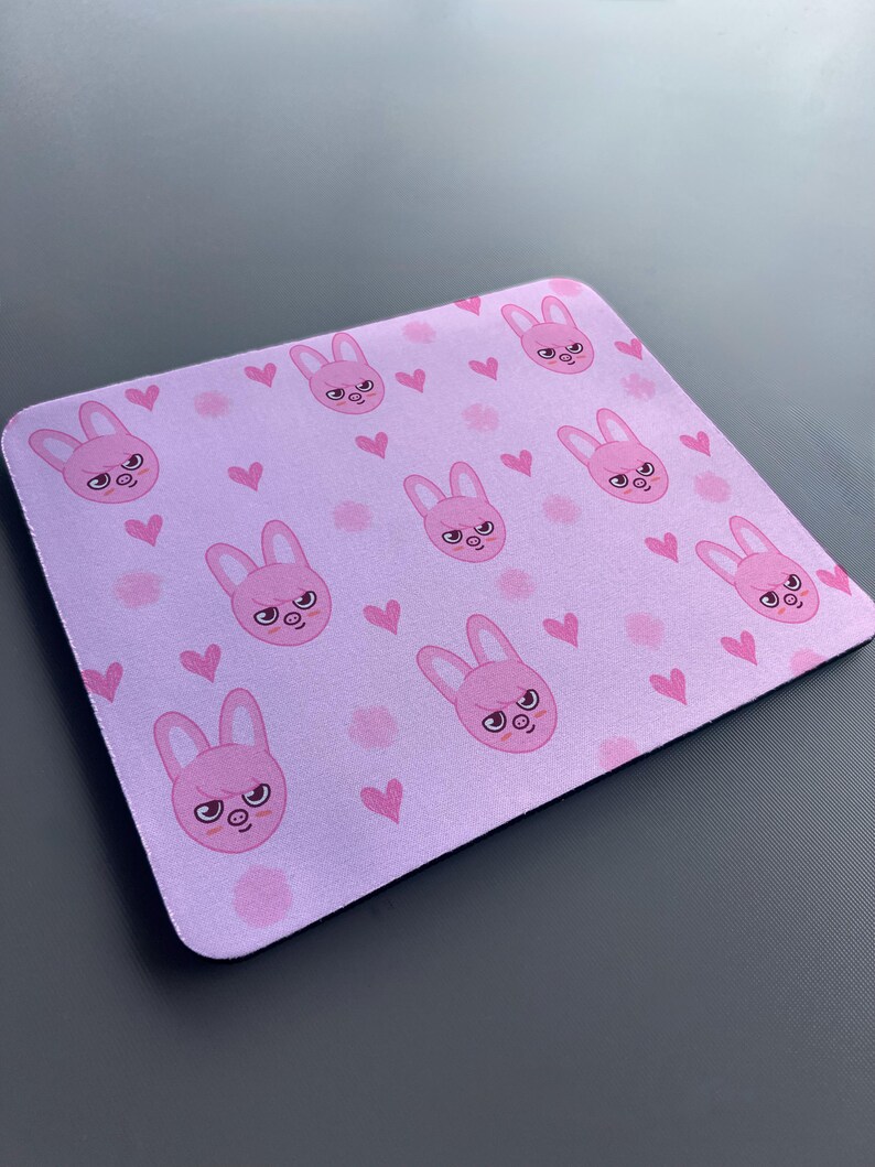 May include: A pink mouse mat with a repeating pattern of pink bunnies with angry expressions and pink hearts.