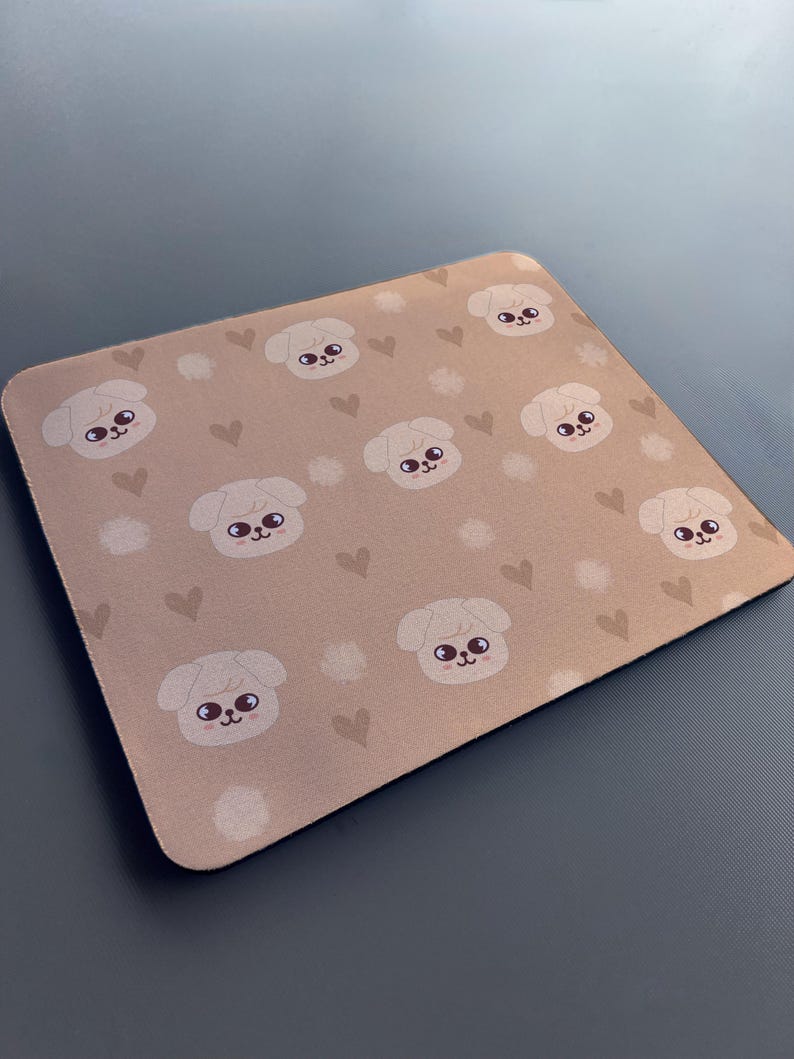 May include: A brown mouse mat with a repeating pattern of white cartoon dogs with brown eyes and pink noses. The background is a light brown with small white and brown hearts.