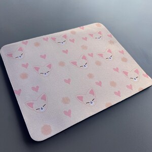 May include: A pink and white mouse mat with a repeating pattern of cartoon foxes and hearts.