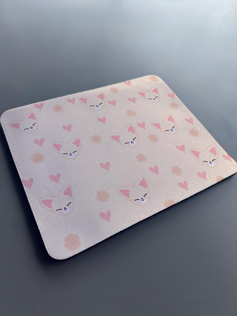 May include: A pink and white mouse mat with a repeating pattern of cartoon foxes and hearts.