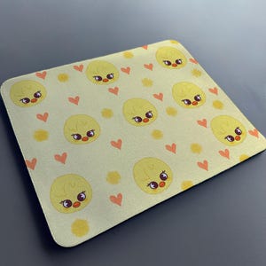 May include: A yellow mouse mat with a repeating pattern of cute cartoon chicks with hearts and yellow flowers.