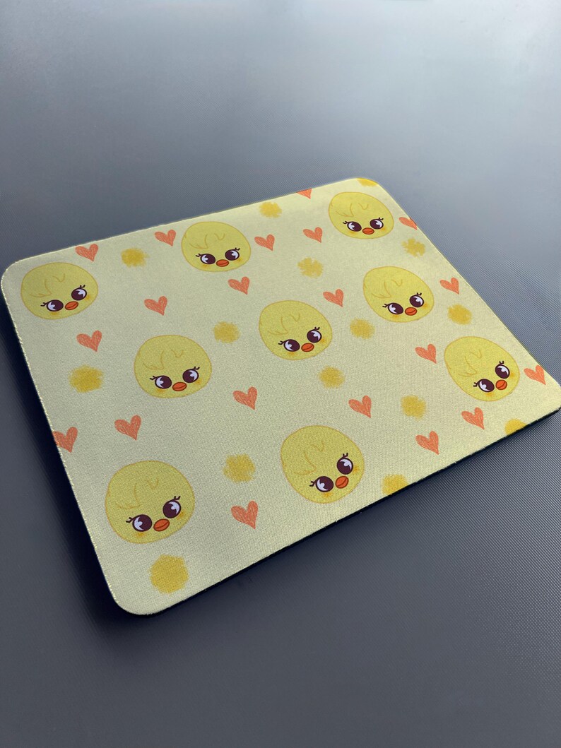 May include: A yellow mouse mat with a repeating pattern of cute cartoon chicks with hearts and yellow flowers.